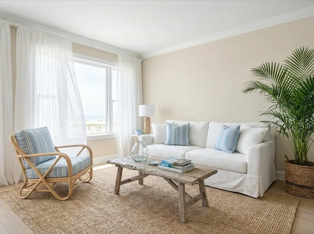 A coastal living room: white sofa, jute rug, rattan chair, blue and sandy tones